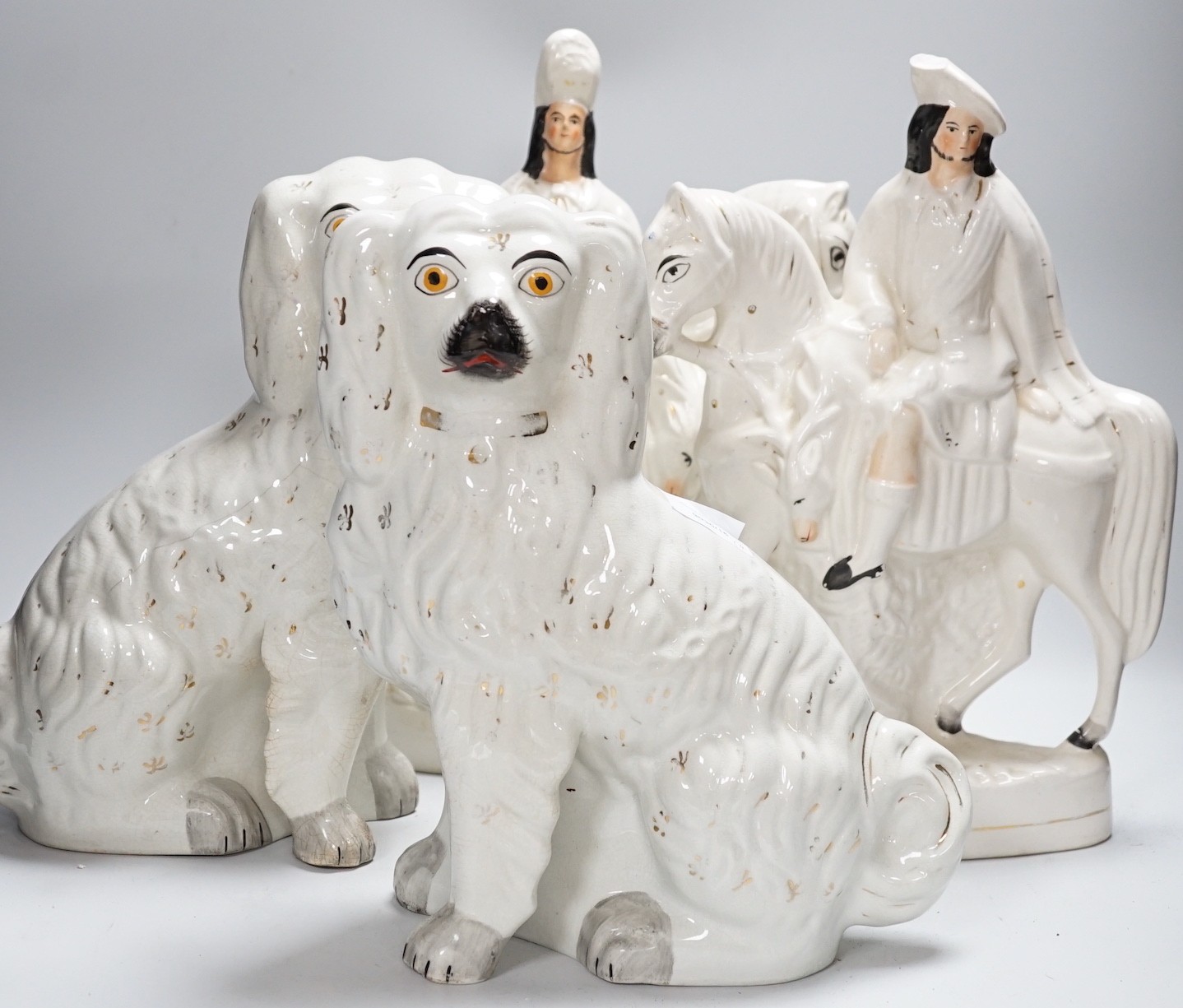 A pair of Staffordshire pottery spaniels, 30cm high, and a pair of equestrian groups, 19th century